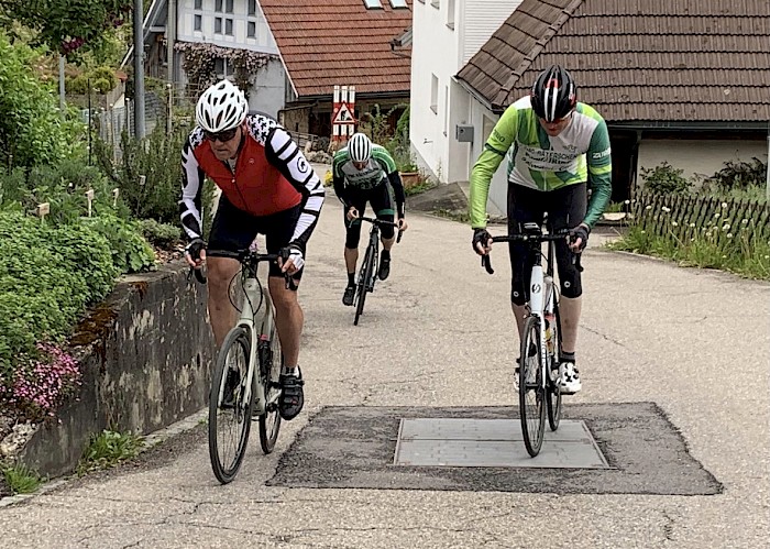 Drei Rennradfahrer kämpfen sich eine Steigung hinauf
