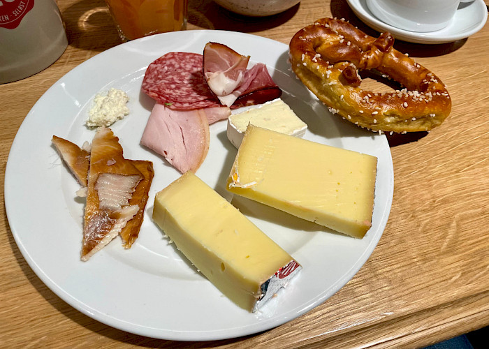 Käse, Wurst und ein Laugenbrezel auf dem Teller beim VMC-Brunch